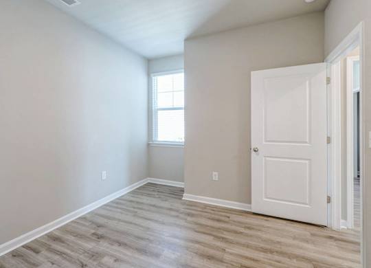 an empty room with a white door and a window