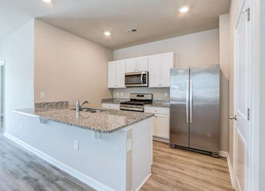 a kitchen with a granite counter top and a stainless steel refrigerator