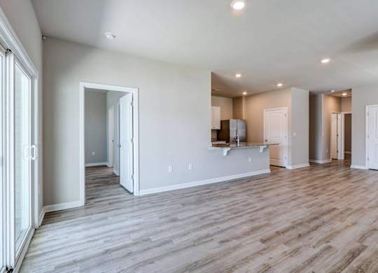 the living room and kitchen of a new home with white walls and wood flooring