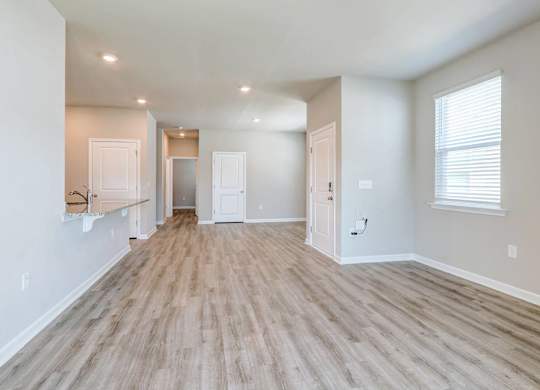 a spacious living room with a hard wood floor and white walls
