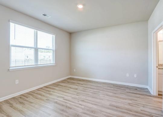 an empty living room with wood flooring and a window