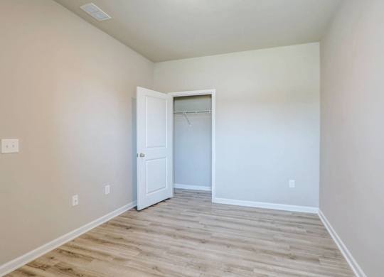 a bedroom with white walls and a closet with a door