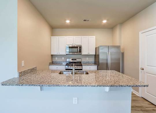 a kitchen with a granite counter top and a stainless steel refrigerator