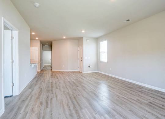 the living room and dining room of an empty house with wood flooring