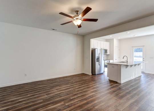 Townhomes near Tanger Outlets in North Charleston, NC - Highland Townhomes - Living Room with High Ceiling, Ceiling Fan, Wood-Style Flooring, and Access to the Kitchen.