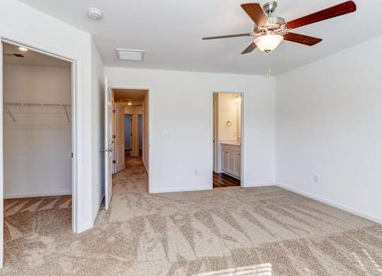 an empty living room with a ceiling fan and a closet