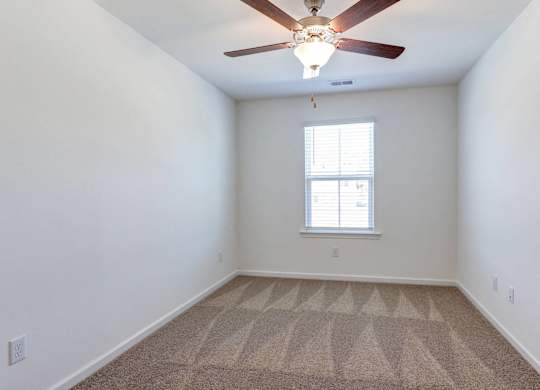 an empty room with a ceiling fan and a window
