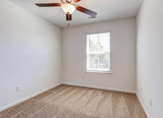 an empty room with a ceiling fan and a window