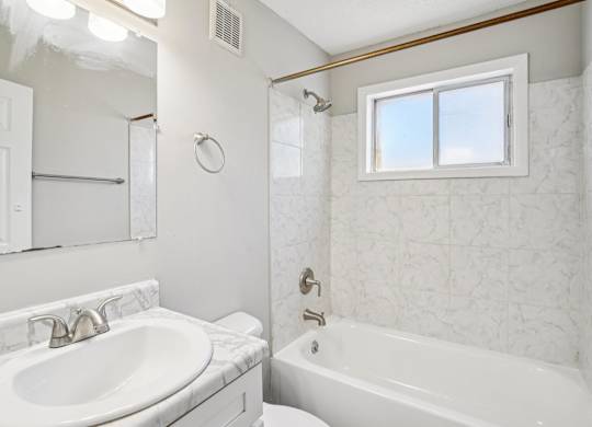 A white bathroom with a sink, toilet, and bathtub.