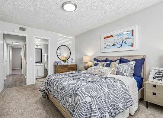 A bedroom with a bed, nightstand, and a painting on the wall.