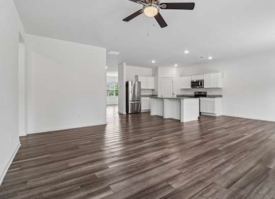 A room with a ceiling fan and wooden flooring.