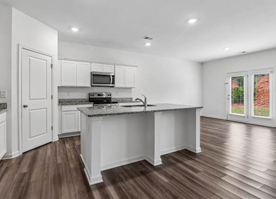 A kitchen with white cabinets and a wooden floor.