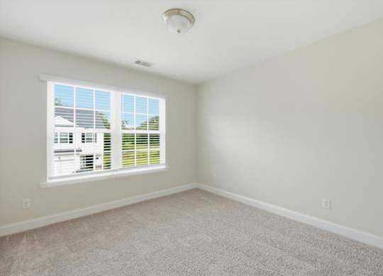 A room with a window and a carpeted floor.