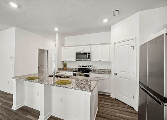 A kitchen with white cabinets and a granite countertop.