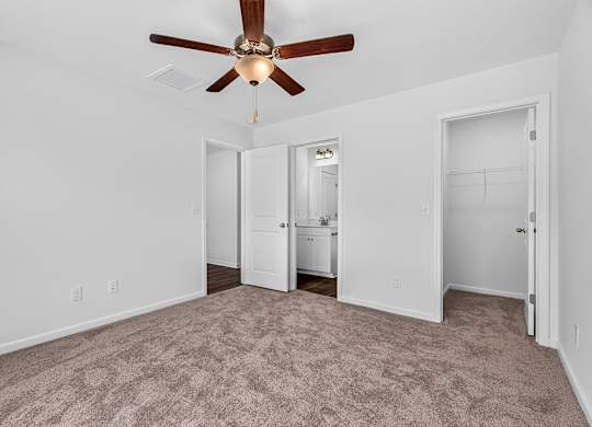 A room with a ceiling fan and carpeted floor.