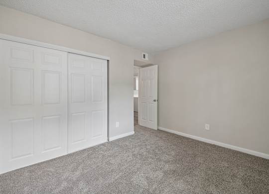 A room with a white door and carpeted floor.