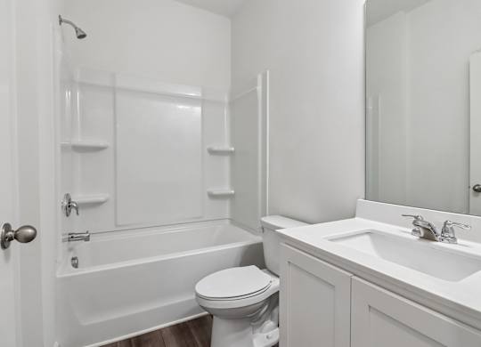 A white bathroom with a toilet, sink, and bathtub.