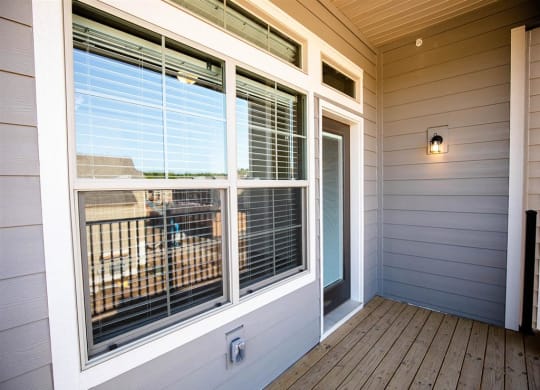 the deck of a home with large windows and a door