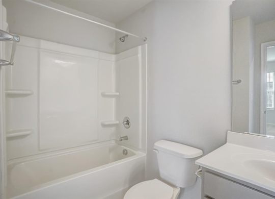 A white bathroom with a toilet, sink, and bathtub.