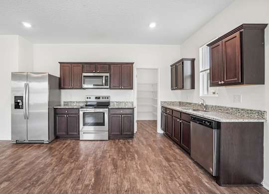 A kitchen with dark brown cabinets and a stainless steel refrigerator.