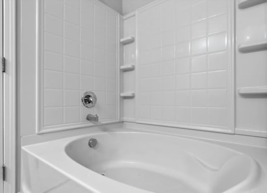 A white bathroom with a white tub and white tiles.