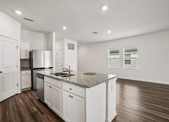 A kitchen with white cabinets and a granite countertop.