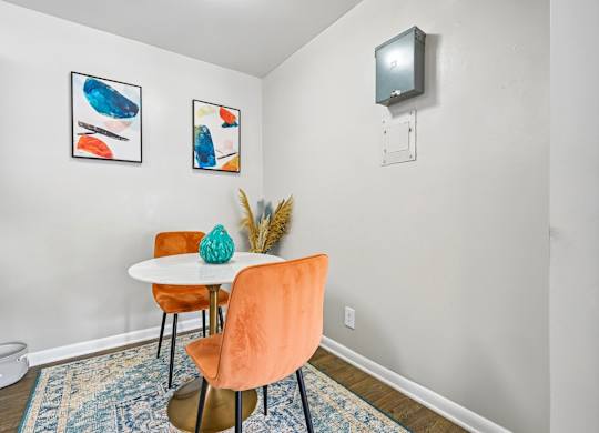 A dining room with a white table and orange chairs.