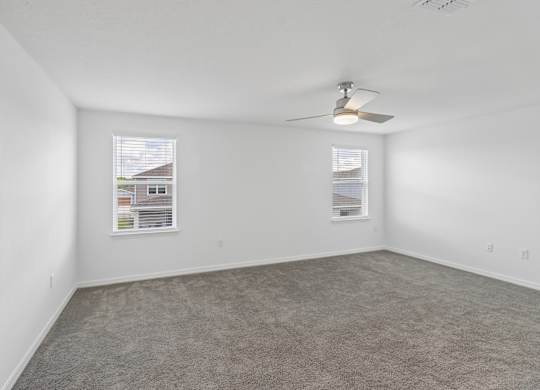 A room with a carpeted floor and a ceiling fan.