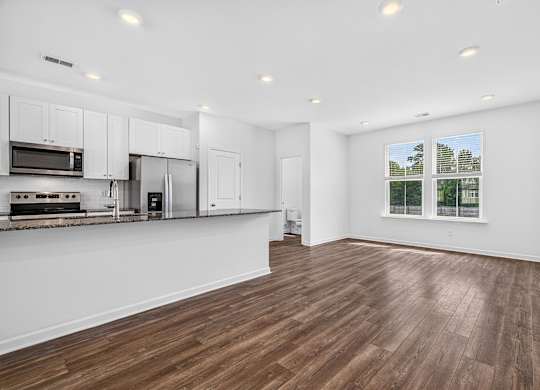 A kitchen with white cabinets and a wooden floor.