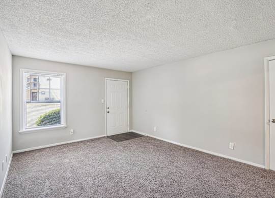 A room with a carpeted floor and two doors.