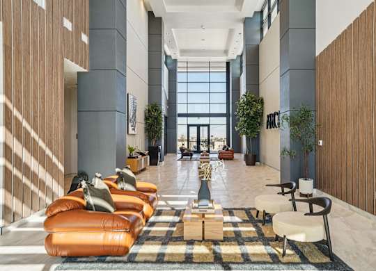 A long hallway with orange chairs and a checkered rug.