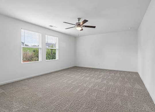 A room with a ceiling fan and carpeted floor.