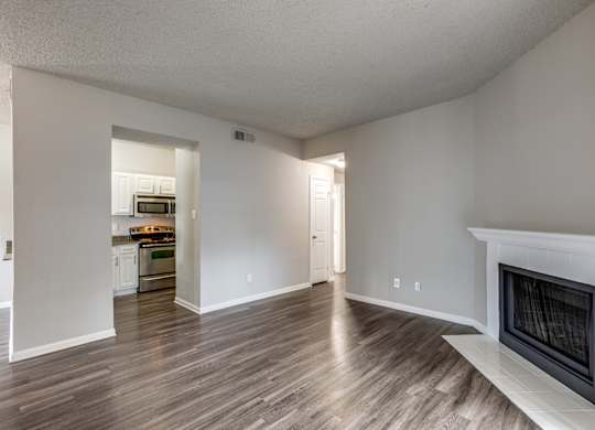 A living room with a fireplace and a kitchen in the background.