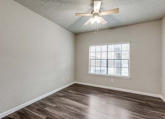 A room with a ceiling fan and a window with blinds.