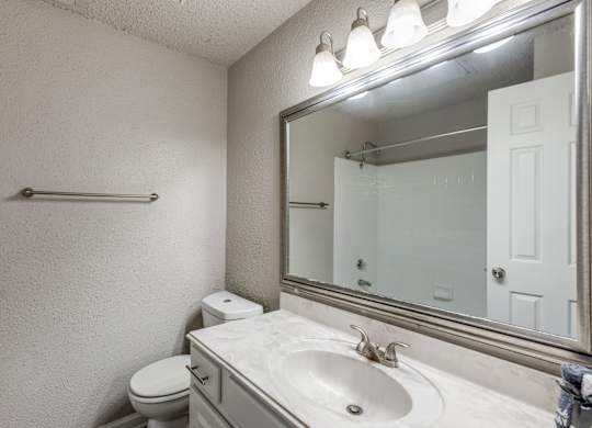 A bathroom with a toilet, sink, and mirror.