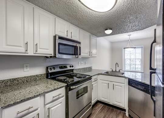 A kitchen with white cabinets and black appliances.