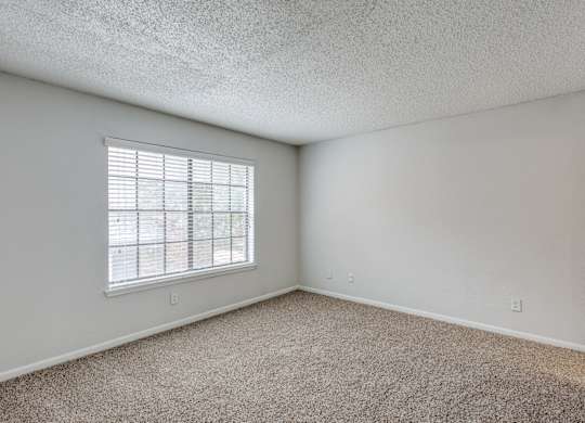 A room with a window and carpeted floor.