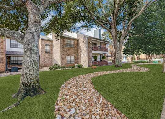 A stone pathway leads through a grassy area in front of a building.