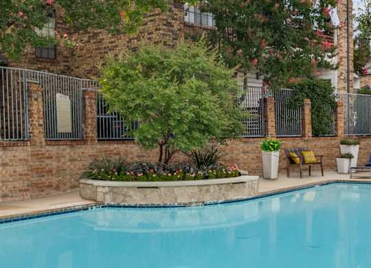 A pool surrounded by a brick wall and a metal fence.