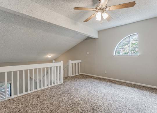 a large lofted bedroom with carpeted flooring and a ceiling fan