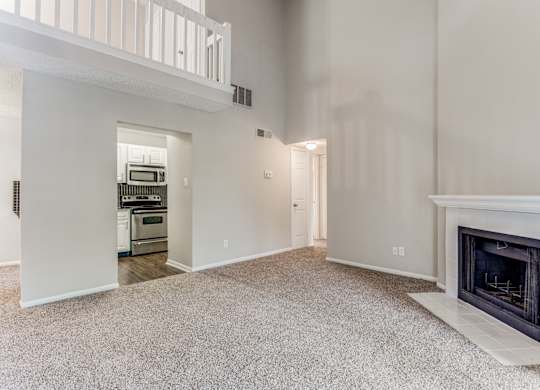 a living room with a fireplace and a kitchen in the background