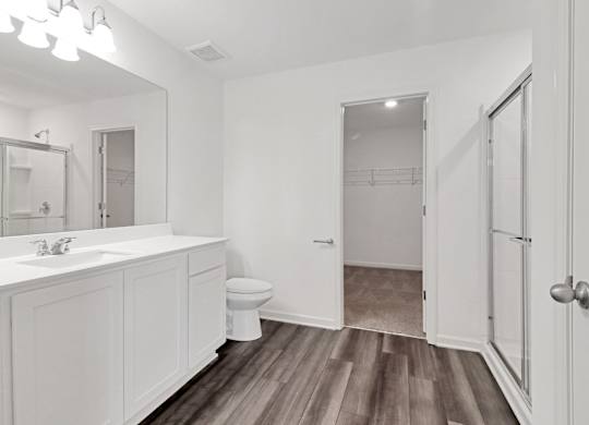 A white bathroom with wood flooring and a white sink.