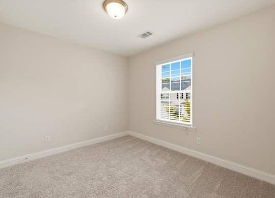 A room with a carpeted floor and a window with blinds.