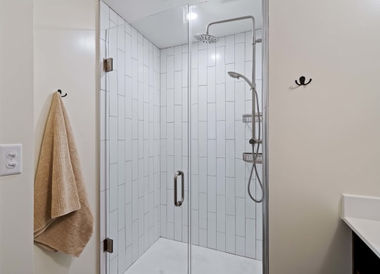 a white tiled shower with a glass door in a bathroom
