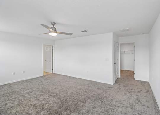 A room with a ceiling fan and carpeted floor.