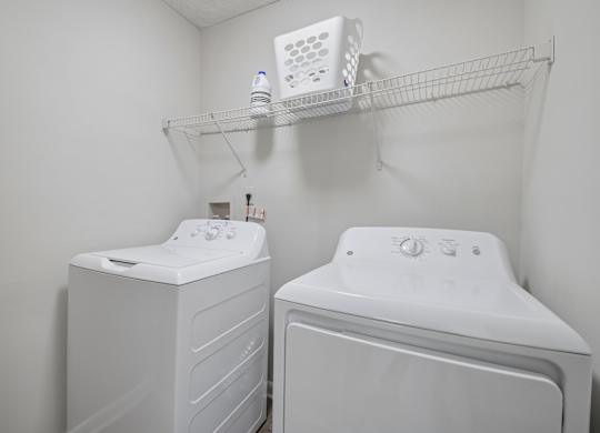 Two white front loading washing machines in a small laundry room.