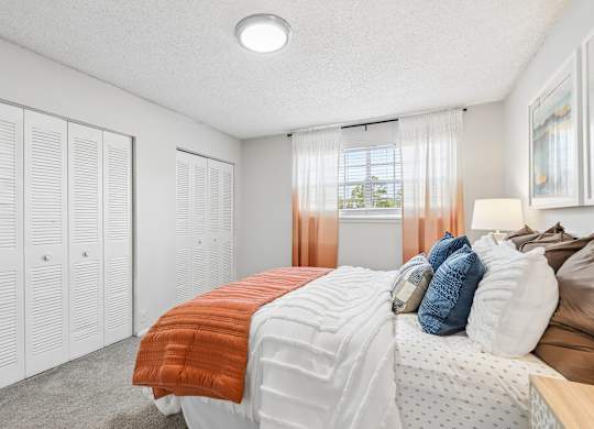 A bedroom with a bed, pillows, and a window with curtains.