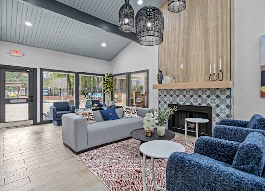 A living room with a grey couch, blue chairs, and a fireplace.