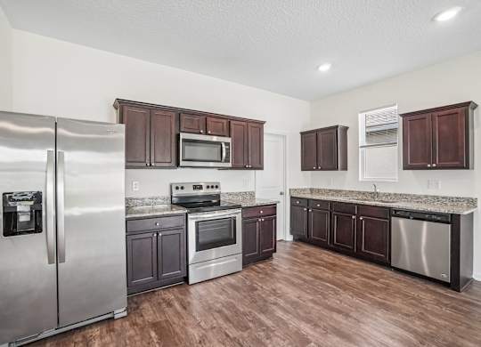 A kitchen with a refrigerator, microwave, oven, and dishwasher.