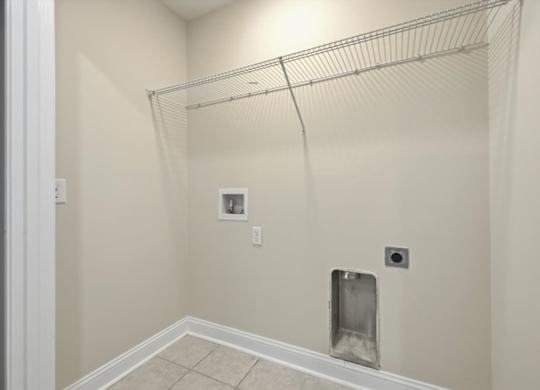 A white wall with a metal rack on top and a white tile floor.